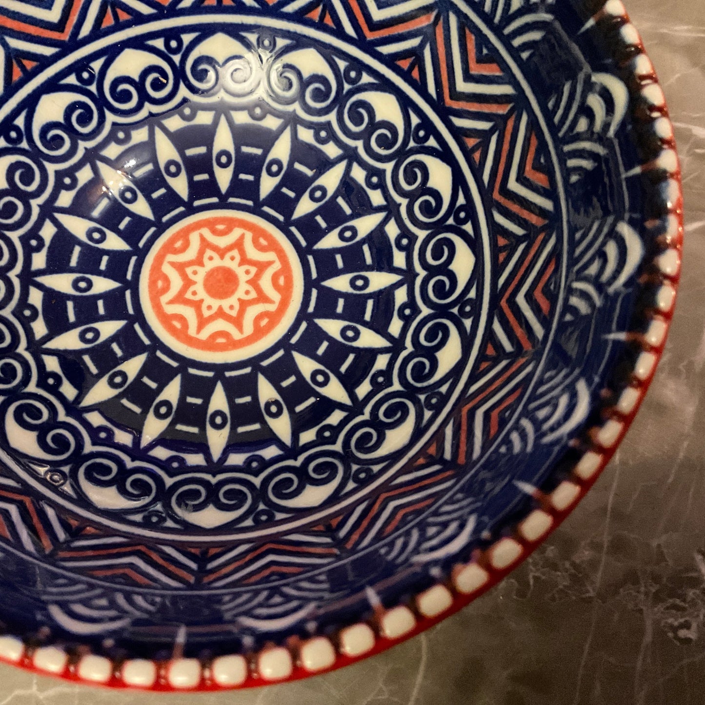 Liten keramikskål i blått, rött och vitt